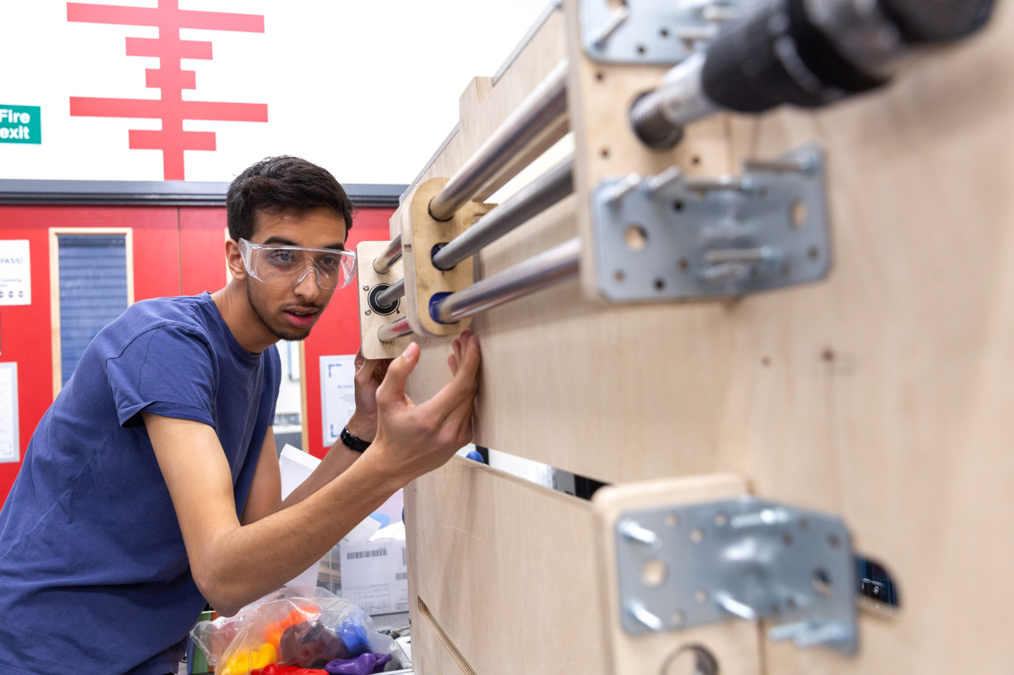 A student adjusts a wooden prototype