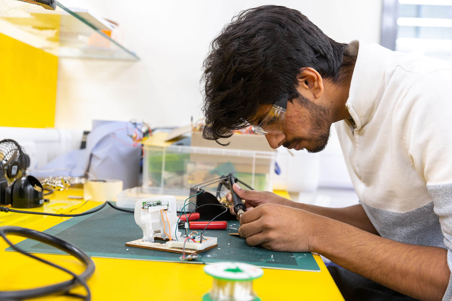 Male student working on electronic parts in workshop