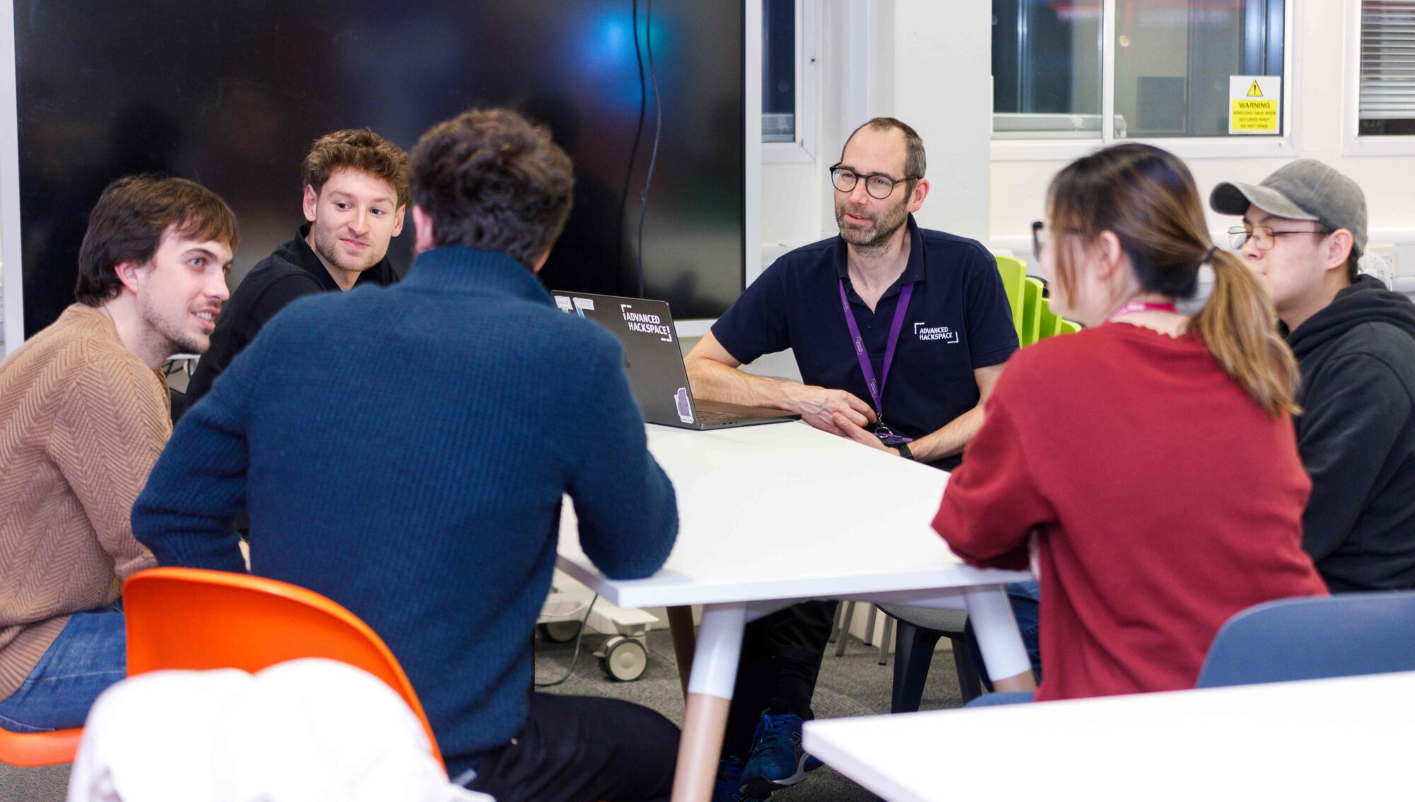 Image of 5 teenagers behind a table looking at the e-scooter they are building